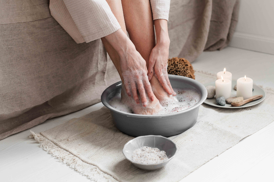 woman soaking and exfoliating her feet to treat and prevent foot corns